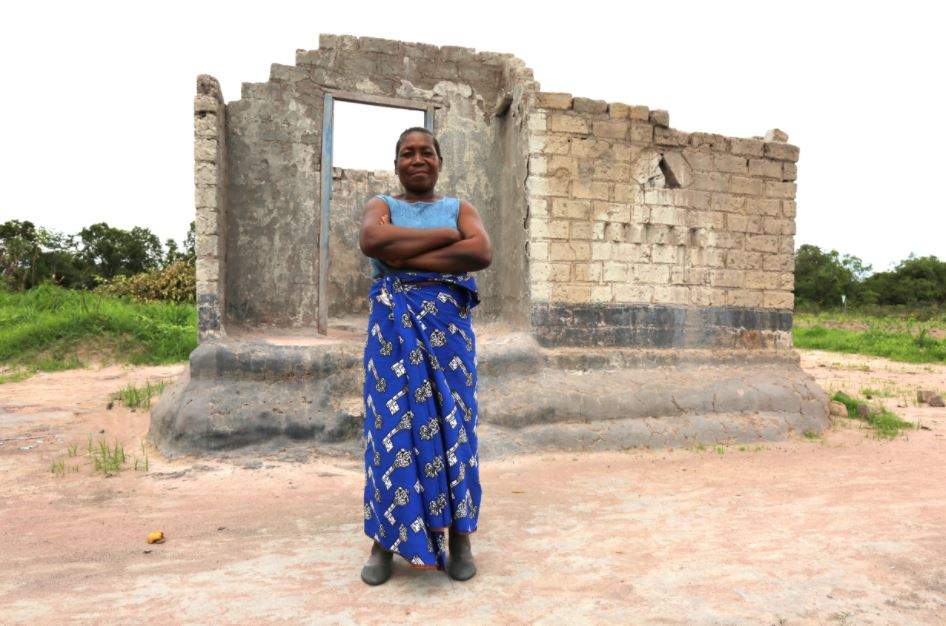 Chileshe stands in front of the remnants of her older, and much smaller home, which hosted a family of eight. Chileshe and her children struggled to make ends meet after her husband passed away. Photo: IFAD